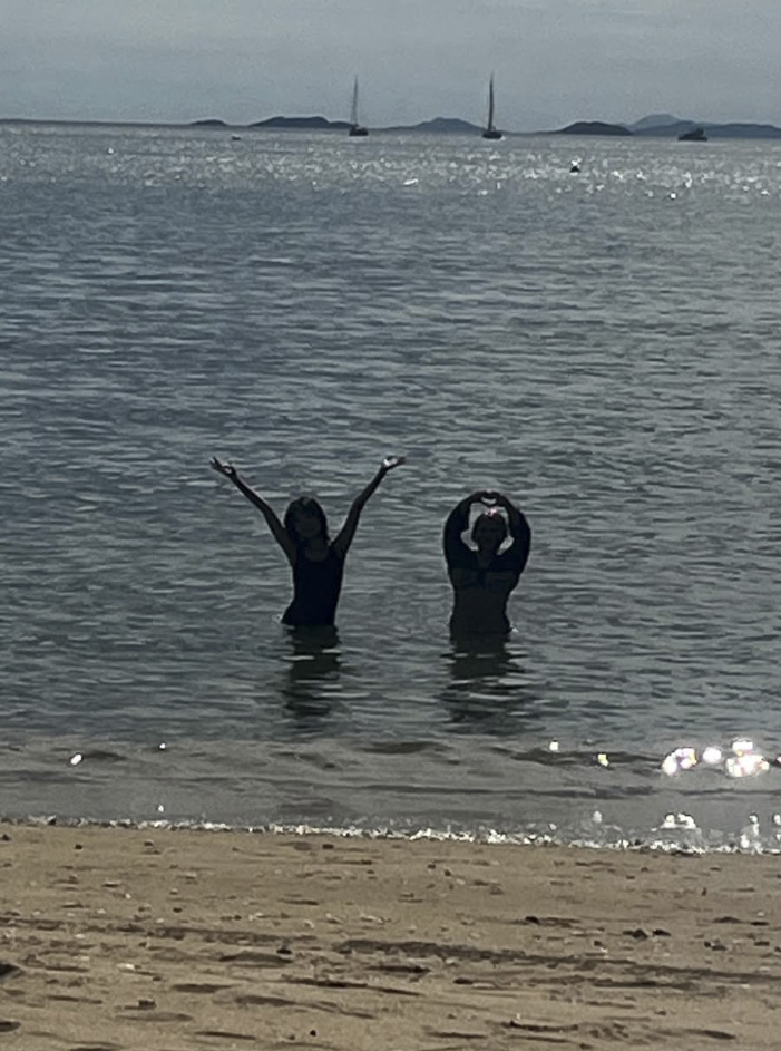 Two friends posing with raised arms in the water at a beach
